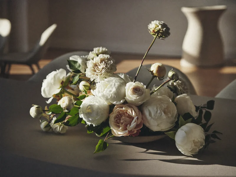Centre de table de mariage aux pivoines blanches, roses et verdure dans une vasque en céramique