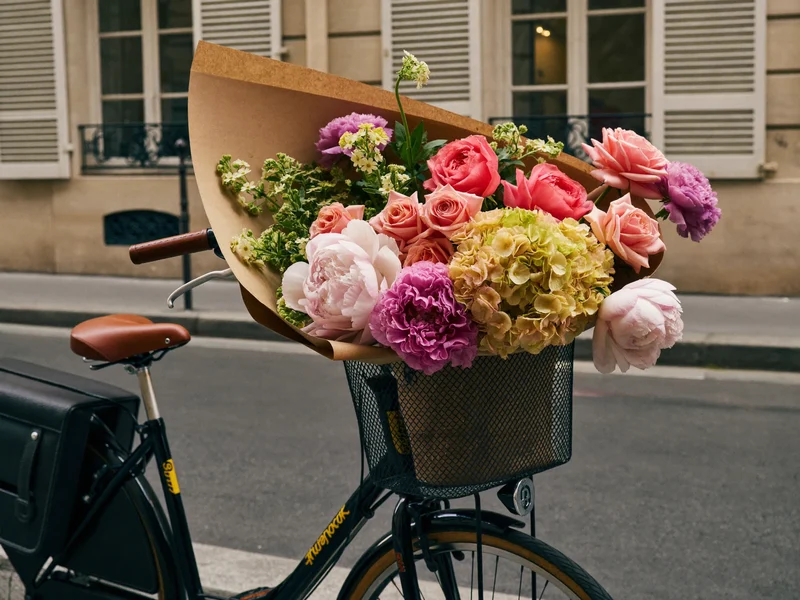 Bouquet emballé de papier dans un panier de vélo cargo, dans une rue tranquille d'une ville française
